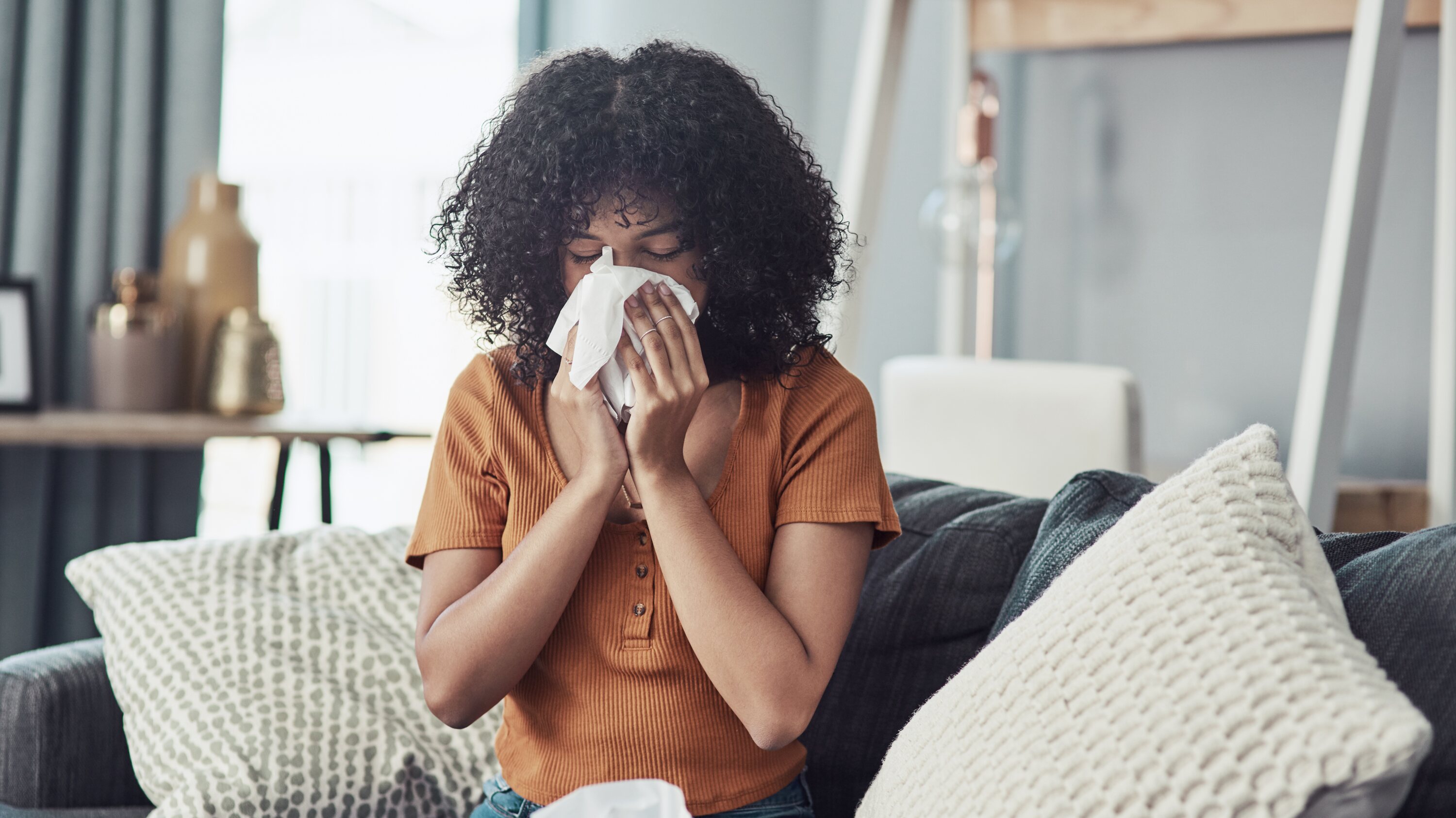 Woman sneezing into tissue